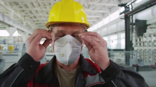 工厂化车间穿着工作服 戴呼吸面罩 戴安全帽 头戴安全护目镜 摆姿势拍照的成年男子的肖像胸像 — 图库视频影像