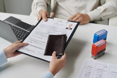 Close-up of woman giving documents to get visa in visa center clipart