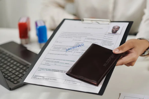 Close-up of specialist giving approved documents and passport to tourist