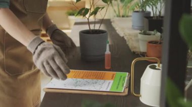 Hasta ev bitkisiyle ilgilenen bir botanikçi, toprağa gübre ekliyor.