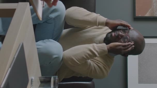非洲裔美国男性患者坐在沙发上 在健康咨询中向治疗师抱怨偏头痛的纵向照片 — 图库视频影像