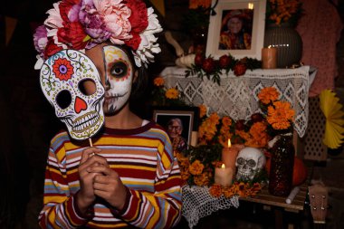 Geleneksel bayram kutlaması sırasında kameraya bakan kafatası maskeli küçük bir kızın portresi