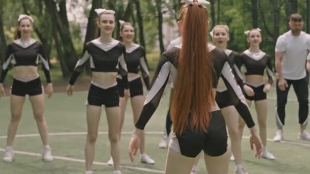 Ryhmä Nuoria Mies Naispuolisia Cheerleadereita Tekemässä Kyykkyjä Harjoitellessaan Valmentajan Kanssa — kuvapankkivideo
