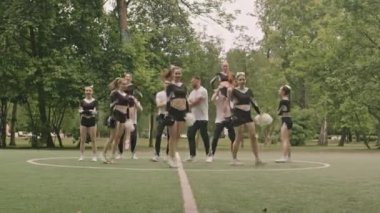 Profesyonel amigo takımının ponpon kızlarla dans etmesi ve açık havada futbol sahasında akrobatik hareketler yapması.