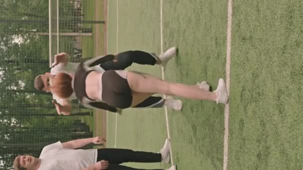 Pionowe Ujęcie Cheerleaderki Stojącej Rękach Męskiego Sportowca Podnoszącego Rzucającego Trzymającego — Wideo stockowe
