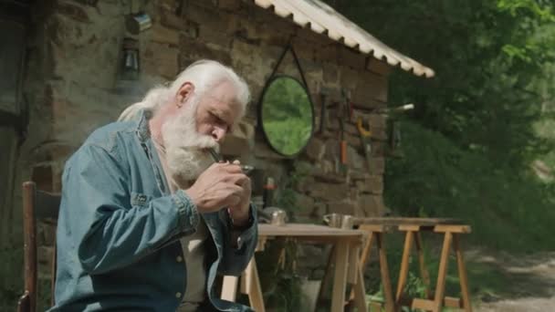 Împușcătură Medie Bătrânului Fumând Țeavă Timp Stătea Lângă Casa Lui — Videoclip de stoc