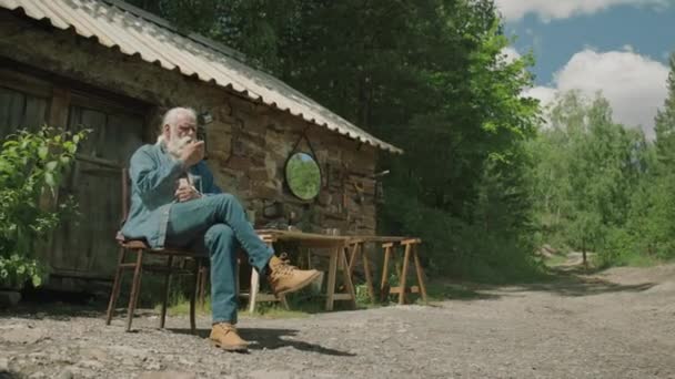 Very Long Shot Relaxed Senior Man Smoking Pipe Sitting Chair — Stock Video