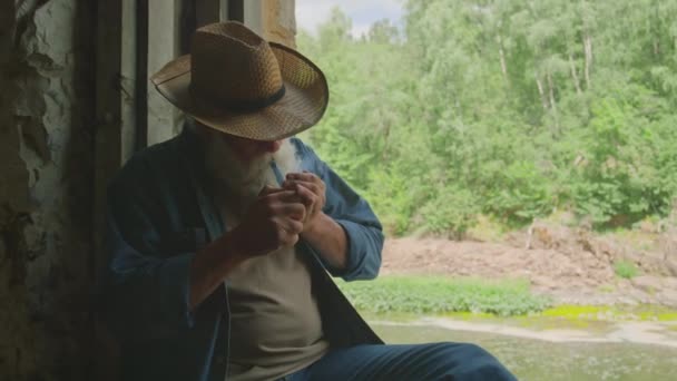 Střední Záběr Uvolněného Důchodce Kouření Potrubí Sedí Vedle Okna Uvnitř — Stock video