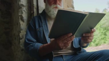 Kapsama alanı dışında otururken, emekli bir adamın bilim kurgu kitabı okuduğu görüntüyü yakınlaştır.