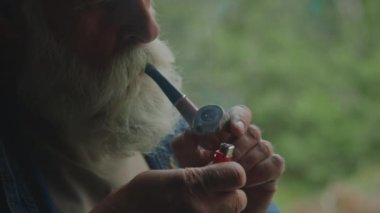 Yaşlı bir adamın doğada dinlenirken sigara piposu içmesine yakın durun.