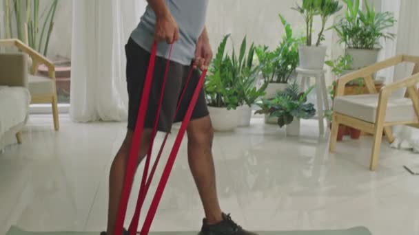 Spor Giyim Giymiş Kaslı Bir Adamın Oturma Odasında Çalışırken Direnç — Stok video