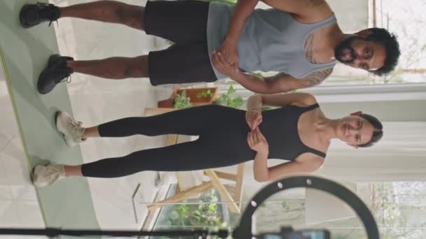 三脚架上的男性和女性健身博客站在智能手机前的垂直照片 在社交媒体的现场直播中与订阅者交流 — 图库视频影像