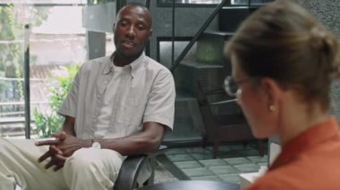 Afrika kökenli Amerikalı adamın zihinsel sağlık sorunlarını açıklayan ve kadın psikoloğun muayenede notlar alırken sorularını cevaplayan omzuna yaslan.