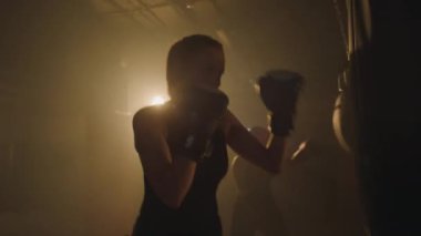 Güçlü bir kadının boks dersi sırasında kum torbasına vurduğu orta boy bir fotoğraf.