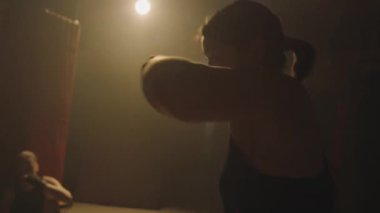 Kısık ateşte antrenman yaparken kadın boksörün yan görünüşü