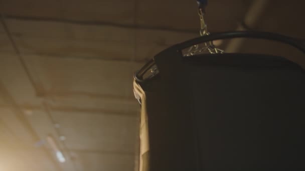 薄暗く点灯されたボクシング 人で掛かるパンチ バッグのクロップ ショット — ストック動画