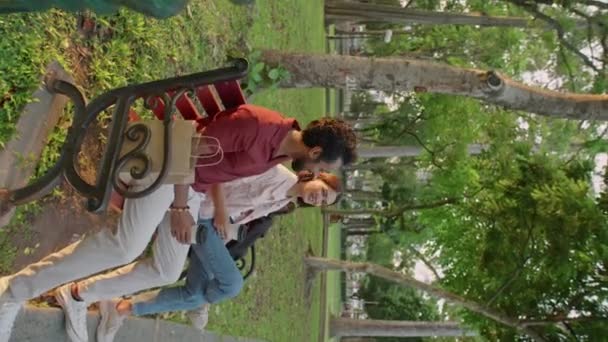 在黄金时段 年轻男女坐在公园的长椅上 一边举着咖啡杯 一边在户外休息 一边进行着充分的讨论 — 图库视频影像