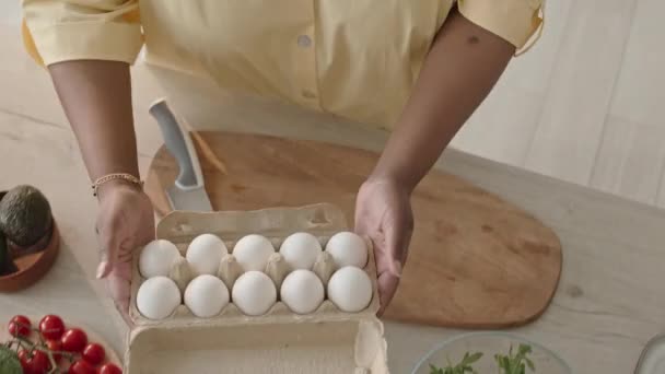 从上至下是一个无法辨认的黑人妇女在厨房桌上下蛋 然后在做健康饭菜的时候拿刀切鳄梨 — 图库视频影像