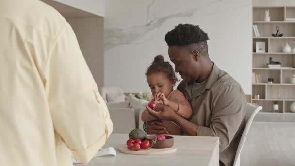 Афроамериканский Папа Сидит Нахмуренной Маленькой Дочерью Пытается Дать Свежие Овощи — стоковое видео