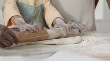 Un kaplı mutfak masasında birlikte yemek pişirirken ailesinin yardımıyla hamuru yuvarlamayı öğrenen küçük çocuğun kişisel olmayan fotoğraflarını çek.