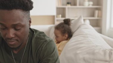 Küçük kızı arkada akıllı telefonuyla oynarken Afro-Amerikan askerinin oturma odasındaki koltukta dizüstü bilgisayar kullanmasını çek.