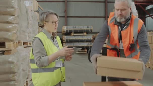 フォアマンと倉庫で働いている間デジタルタブレットを使用して女性マネージャーの中長ショット — ストック動画