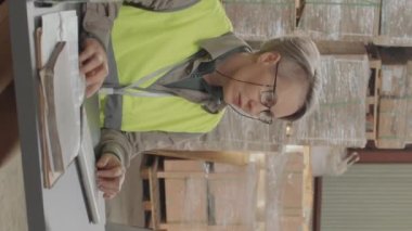 Kadın yöneticinin depoda çalışırken bilgisayar kullanmasının dikey görüntüsü