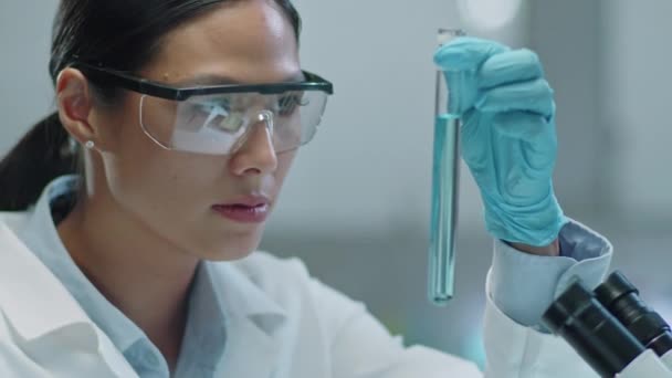 Азиатская Женщина Ученый Защитных Очках Перчатках Изучает Синий Химикат Пробирке — стоковое видео
