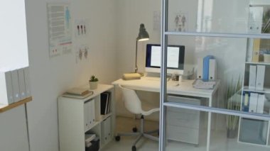 Modern tıp bürosundaki cam bölme duvarının arkasındaki beyaz masada masaüstü bilgisayarından çekilen kimse yok.