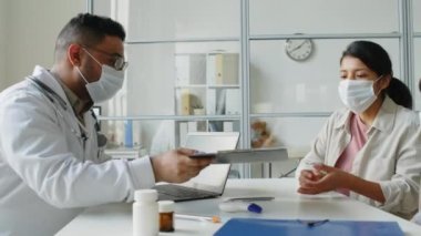 Modern klinikte küçük bir kızla doktor randevusu alırken İspanyol genç bir kadının tıbbi anlaşma imzalaması.