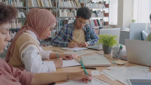 Cintura Jóvenes Estudiantes Migrantes Diversos Sentados Escritorio Biblioteca Moderna Escribiendo — Vídeos de Stock
