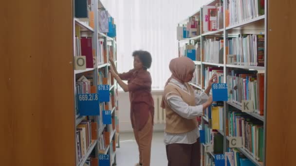 Panorámica Estudiantes Multiétnicos Que Buscan Libros Estanterías Biblioteca Universitaria — Vídeo de stock