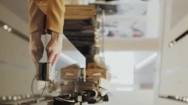 Modern giyim mağazasının tezgahında kredi kartıyla ödeme yapan çekici, kızıl saçlı bir kadının orta boy dikey yavaşlığı ve satın alınmış eşyalarla dolu kağıt torbaları ona vermesi.