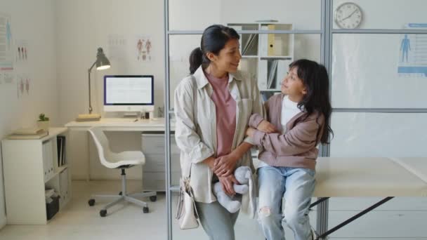 西语裔小女孩与妈妈在现代轻儿科医生办公室摆姿势拍照的中等肖像 — 图库视频影像