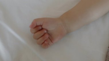 Beşikteki yatak çarşafında uzanan tanınmayan küçük çocuğun sıkıca sarılmış küçük eli.