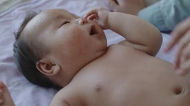 Tanımlanamayan bir anne, küçük oğlunun karnını okşarken kadın sırtüstü yatıp merakla etrafına bakıyor.