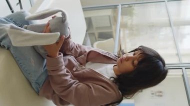 Hastanede doktoru beklerken en sevdiği pelüş oyuncağıyla oynayan utangaç küçük kızın dikey orta pozu.