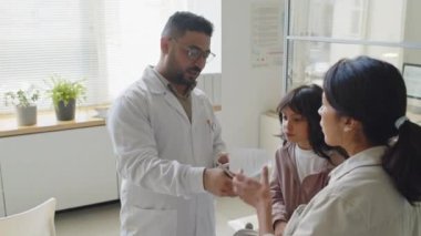 Erkek çocuk pratisyeninin, küçük kızlara el yazısıyla reçete yazması klinikte check-up randevusu alırken anne olması.