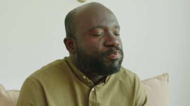 Psikolojik danışmanlık sırasında ağlayan ve göz yaşlarını kağıt peçeteyle silen sinirli Afrikalı Amerikalı adamın göğüs yukarı çekimi.