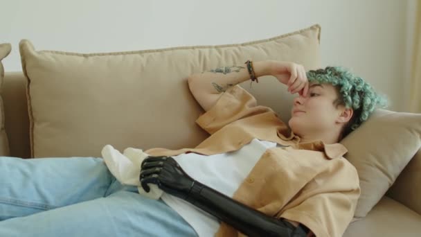 ソファーに横たわる義足の腕と青い髪を持つ悲しい遺伝子Z少女 ナプキンを抱え セラピーセッション中に感情について話す — ストック動画