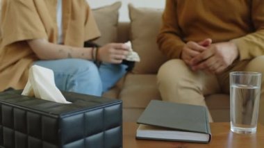 Erkek terapistin, danışmanlık sırasında kanepede otururken protez kollu bir kadının elini tutarken çekilen zoom portresi.