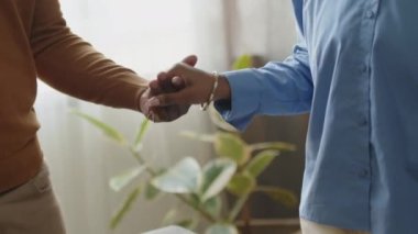 Afro-Amerikalı bir kadının başörtüsüyle ailesiyle el ele tutuşurken ve evde tatil yemeği yemeden önce gözleri kapalı dua ederken.