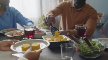 Afro-Amerikan bir babanın kızına mısır koyarken, evde şenlikli bir akşam yemeğinde çocuğa baktığı görüntüler.