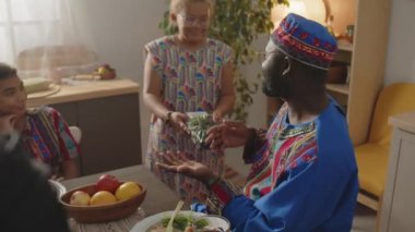 Şirin Afrikalı Amerikalı bir kız babasına hediye paketi ve el yapımı tebrik kartı veriyor. Kwanza tatilini evde ailesiyle kutlarken gülümsüyor ve el çırpıyor.