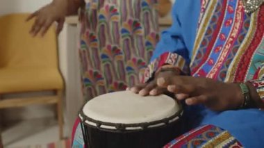 Afrika kökenli Amerikalı bir adamın dashiki kaftan giyip, kufi gülerken ve davul çalarken küçük kızının evde Kwanzaa 'da dans ettiğini çekeceğiz.