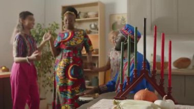 Neşeli Afrikalı Amerikalı anne ve iki kız dashiki 'de babamızın çaldığı davullarla gülerek ve dans ederek evde Kwanza' yı kutluyorlar.