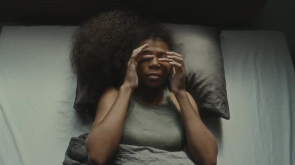 彼女のベッドに横たわっている黒人のティーンガールのトップダウンショット こすり目とストレスに苦しんでいる間 天井を見つめている — ストック動画
