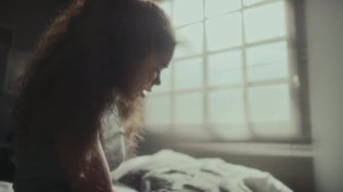 Üzgün Afro-Amerikalı kız, kafasında ellerle oturuyor, telefonla mesajlar okuyor ve yatak odasında endişeleniyor.