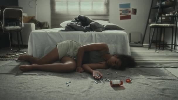 Zoom Toma Adolescente Afroamericana Acostada Suelo Dormitorio Con Pastillas Dispersas — Vídeo de stock