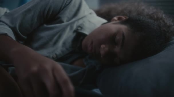悲伤的非洲裔美国少女晚上躺在床上 在手机上打滚 然后抱着膝盖 闭上眼睛 — 图库视频影像